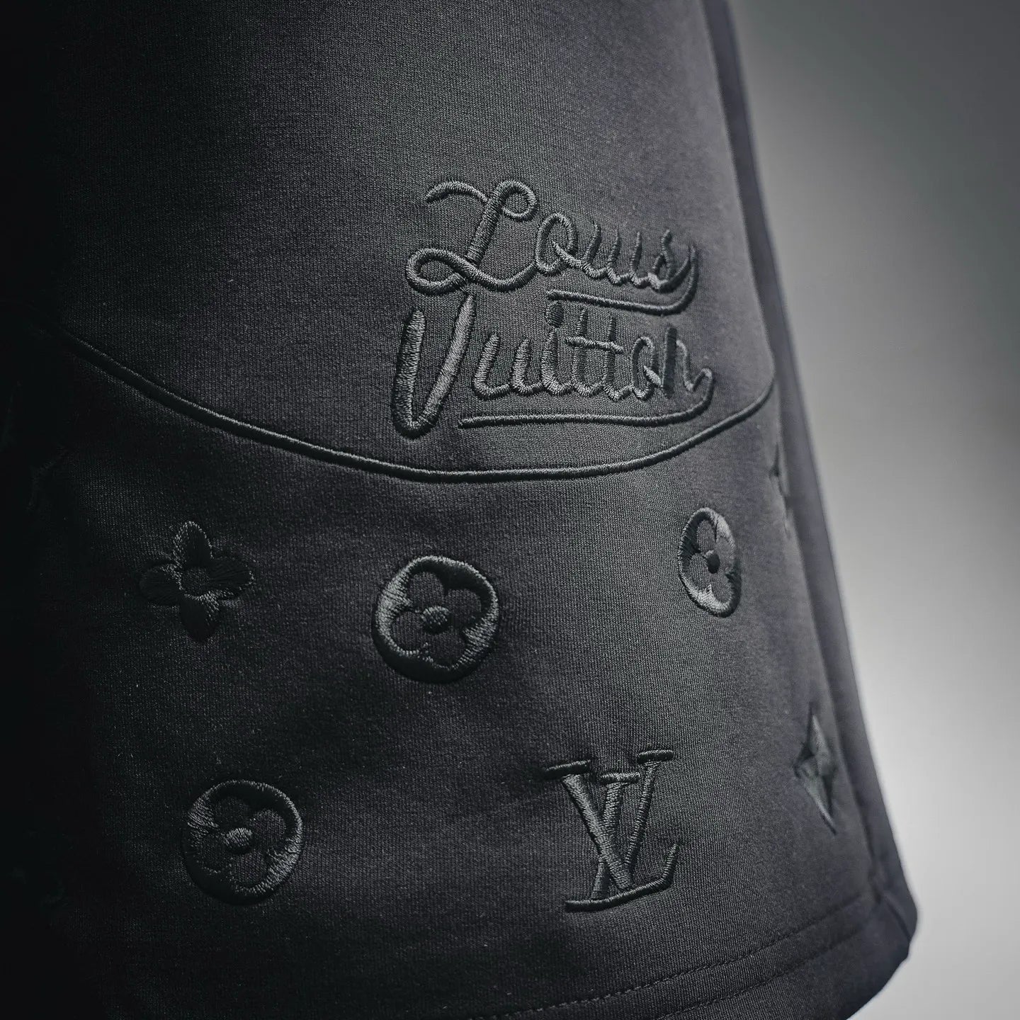 Black shorts with 'Louis Vuitton' script and small LV monogram emblems