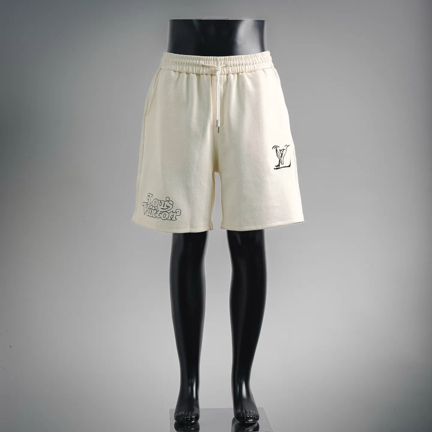 Cream elastic-waist shorts with drawstring, side pockets, and small logo print