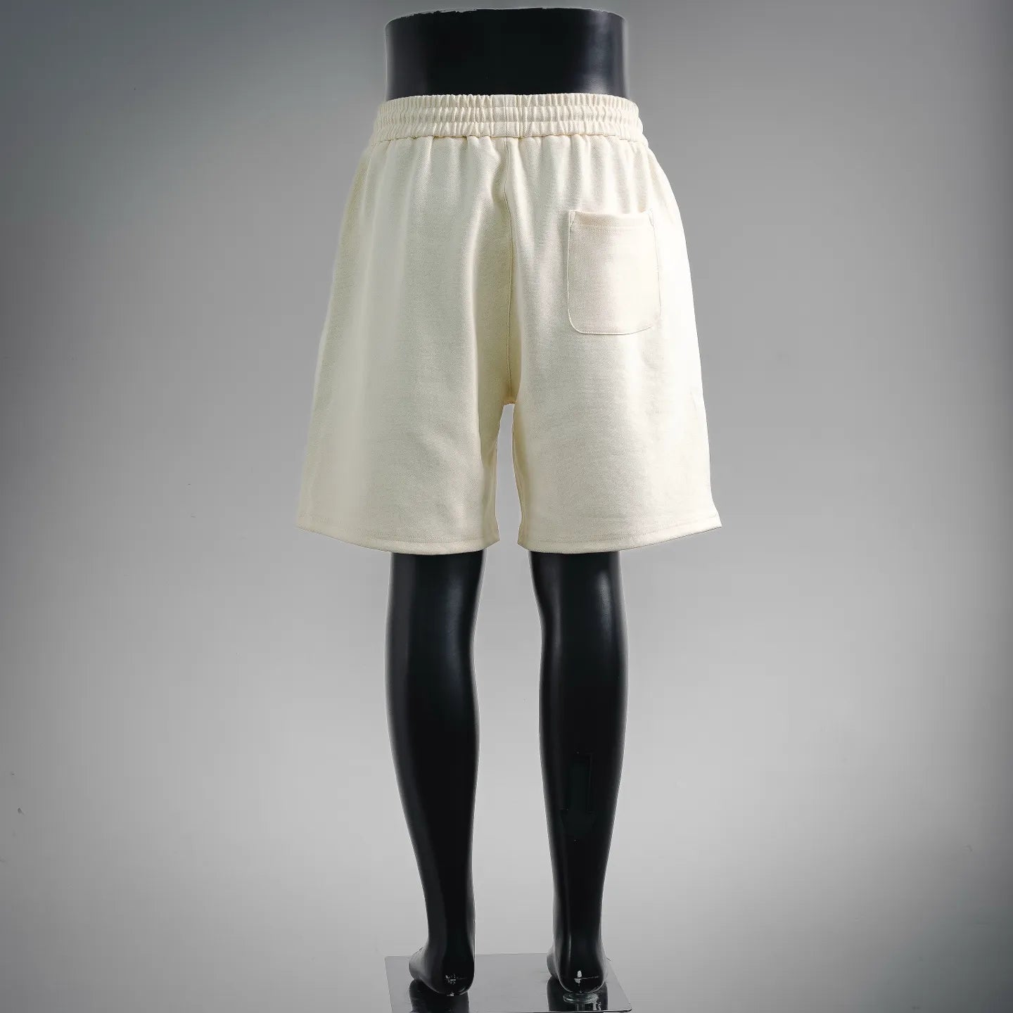 Cream elastic-waist shorts with drawstring and front pocket; clean back view