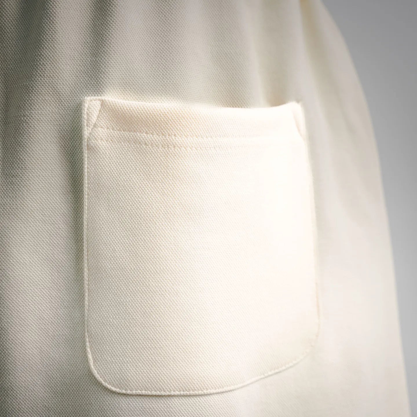 Cream shorts with curved front pocket opening; stitched seam detail