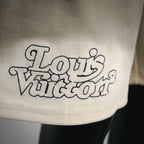Cream shorts featuring a dark Louis Vuitton “World” style logo graphic on the leg