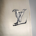 Cream shorts with a dark Louis Vuitton logo graphic print on the leg