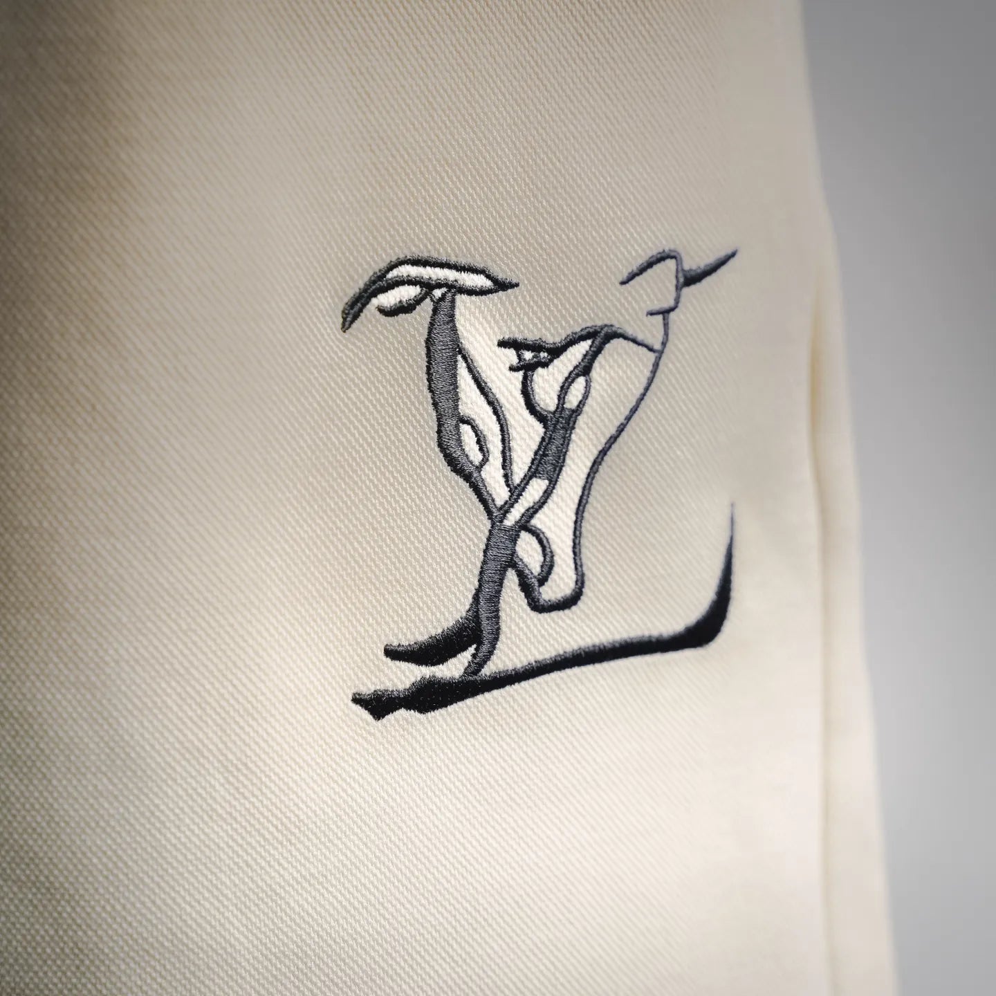 Cream shorts with a dark Louis Vuitton logo graphic print on the leg