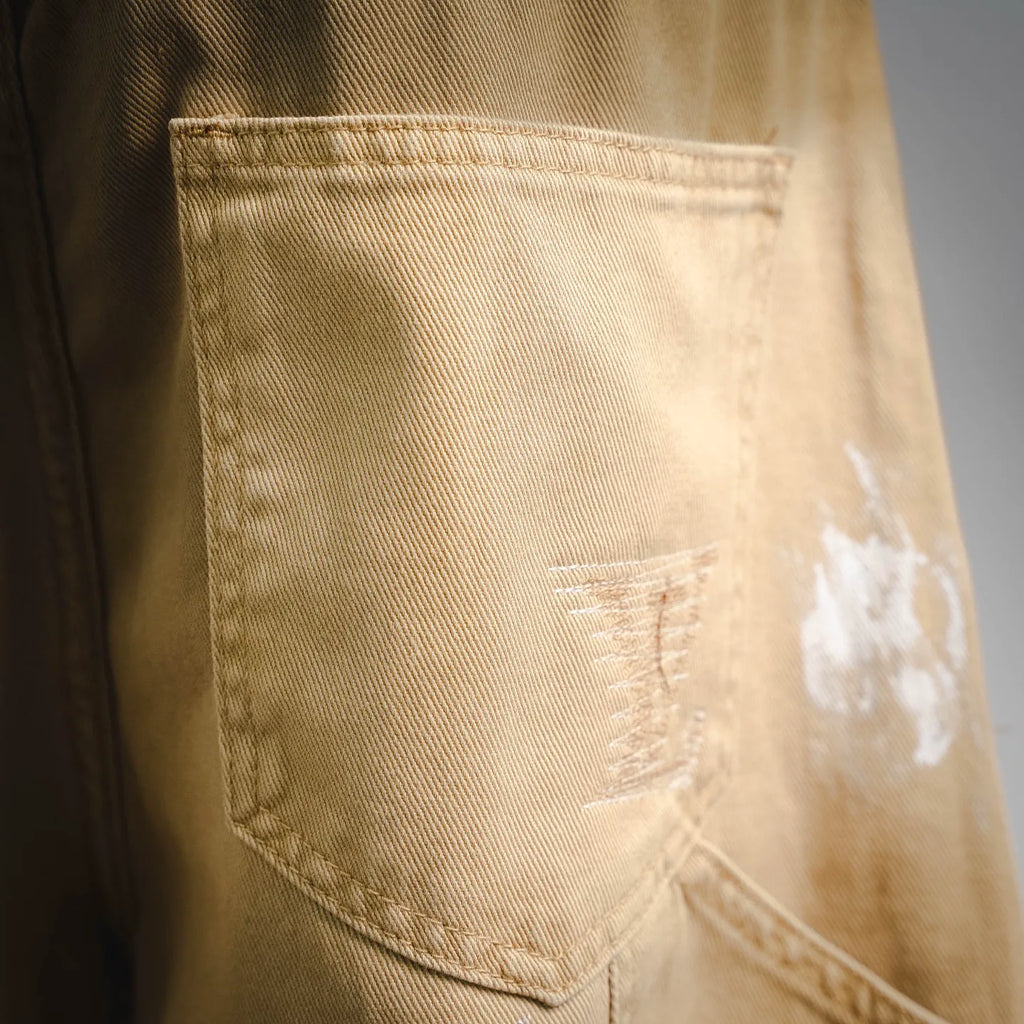 Beige LV shorts patch pocket with visible stitching and light distressing