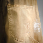 Beige LV shorts patch pocket with visible stitching and light distressing