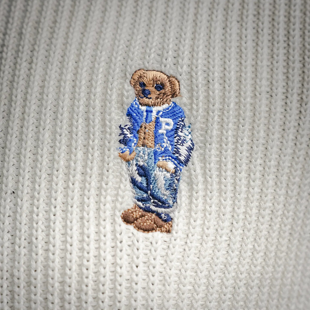 Off-white knit polo with embroidered blue-and-brown bear applique