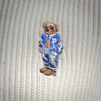 Off-white knit polo with embroidered blue-and-brown bear applique