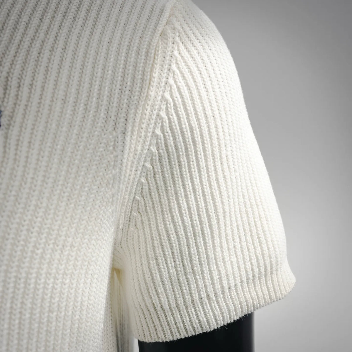 Off-white knit short-sleeve polo with ribbed sleeve cuff and side seam