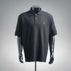Dark navy polo shirt with button placket and small pink embroidered logo on chest