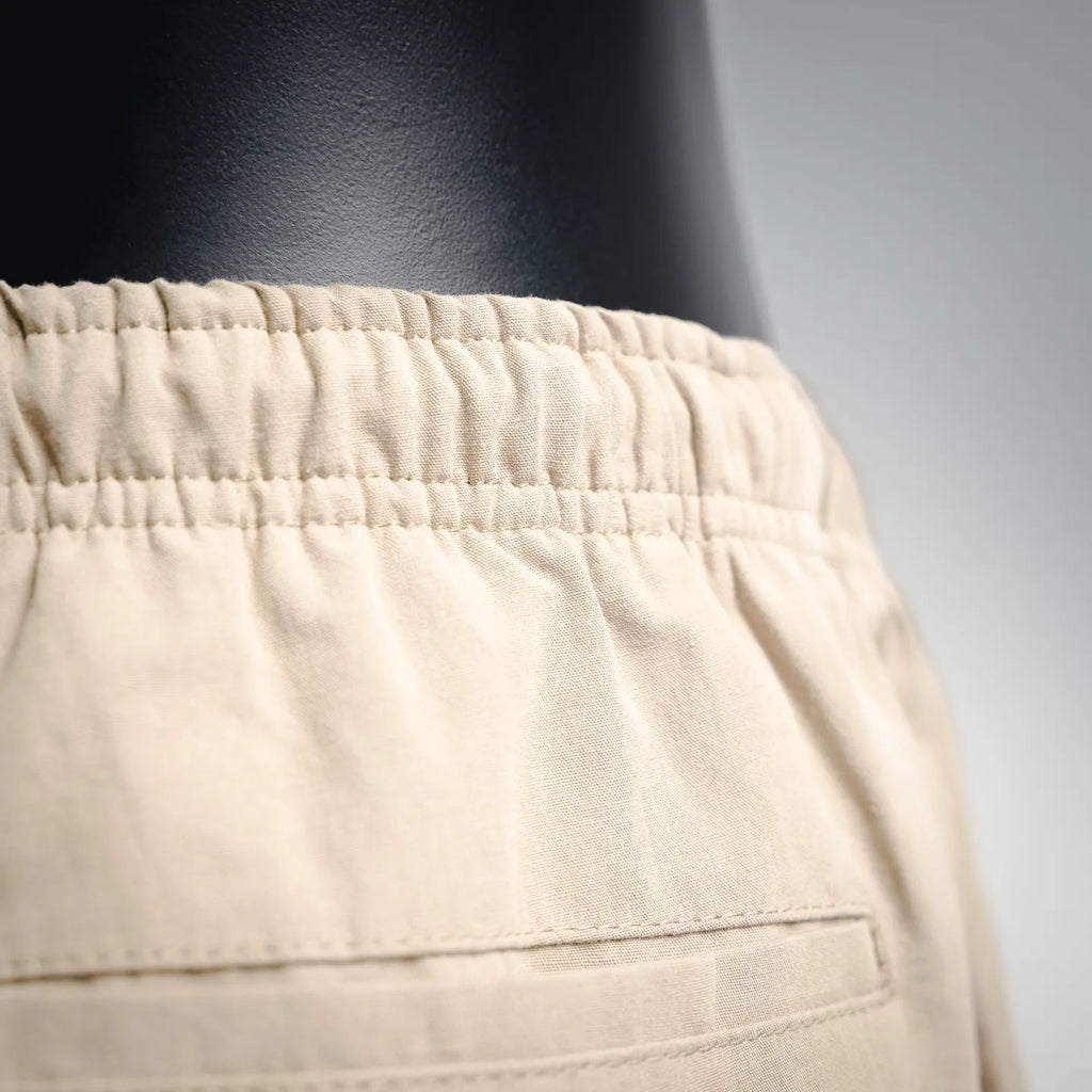 Beige pants with elastic waistband and stitched front pocket seam