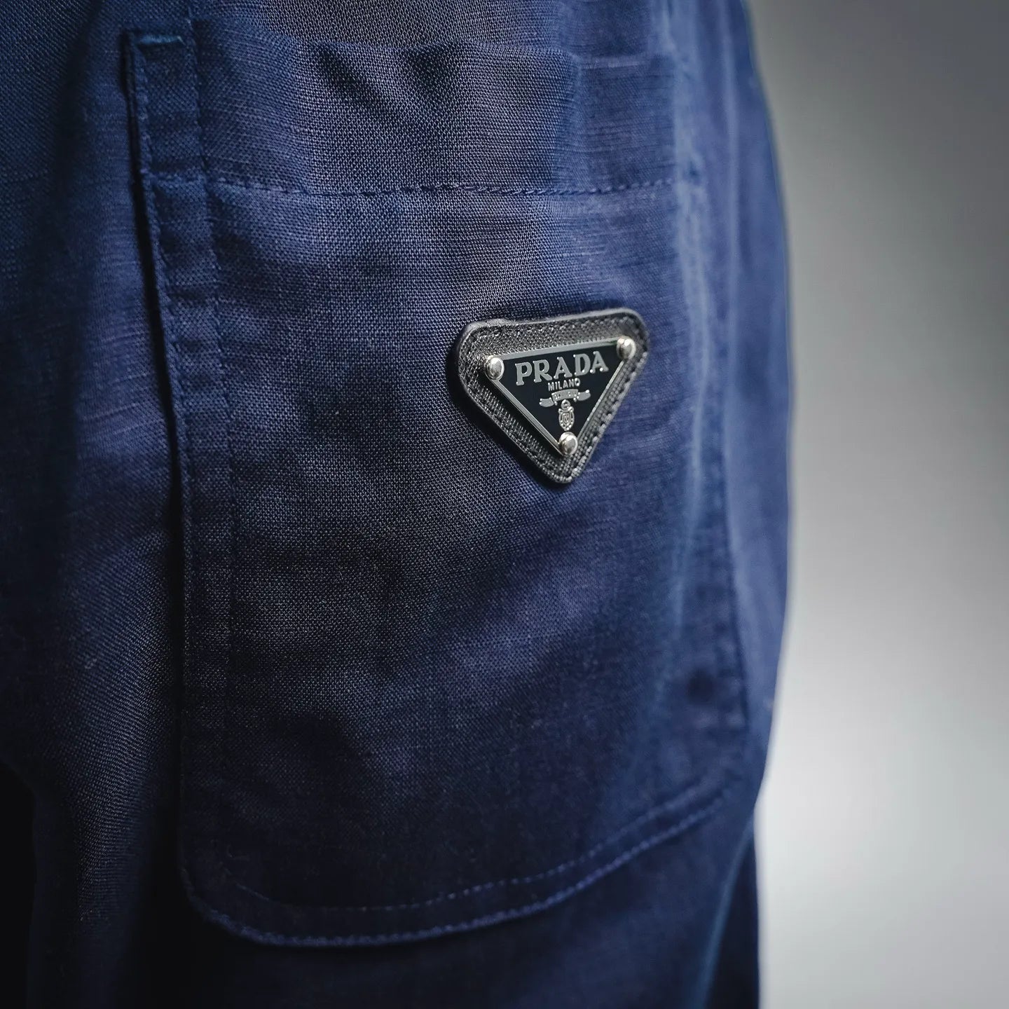 Prada pants back pocket detail with Prada logo patch in dark blue