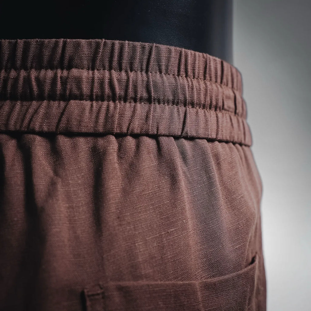 Prada pants waistband close-up with elastic band and textured dark burgundy fabric