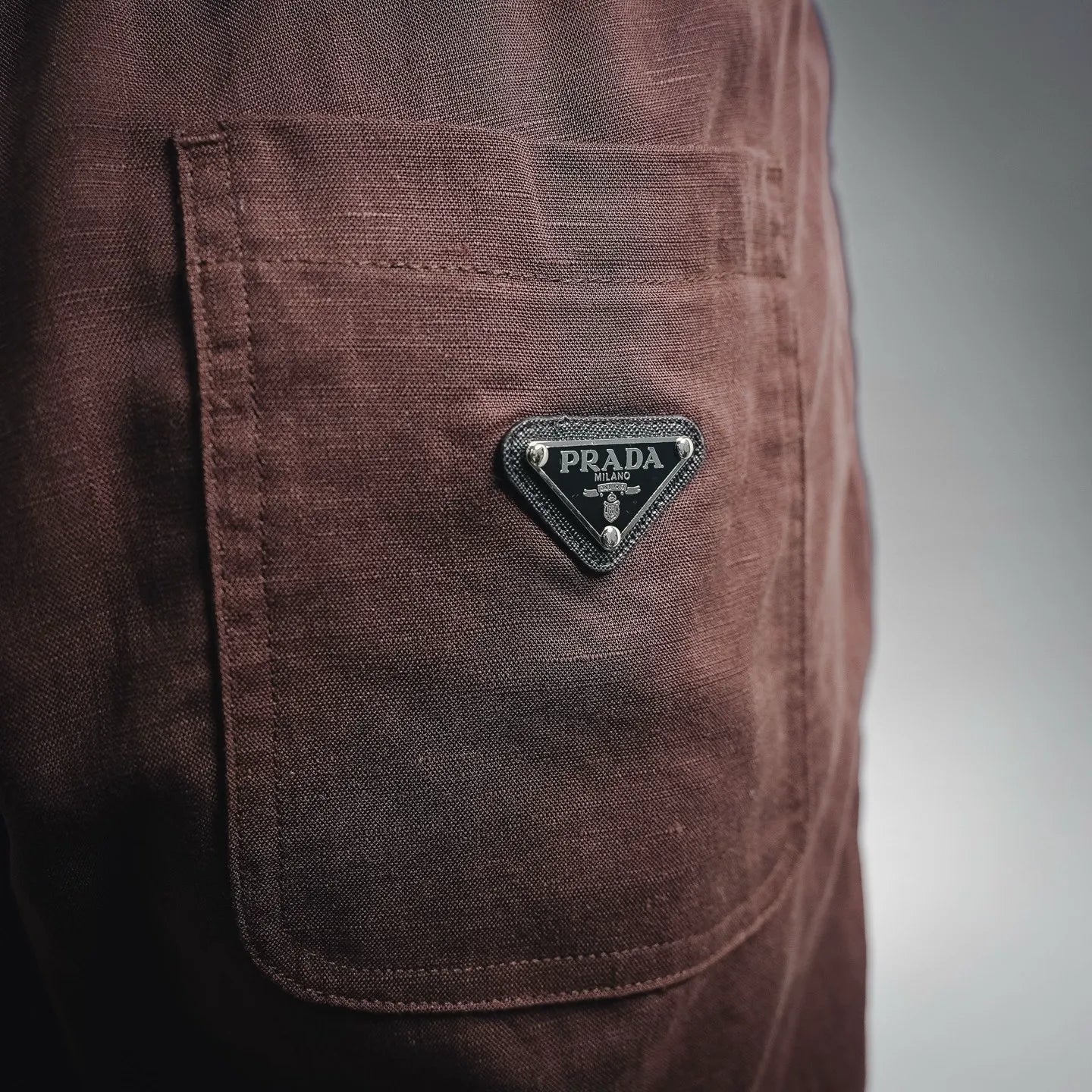 Prada pants side patch pocket with Prada logo badge on dark burgundy fabric