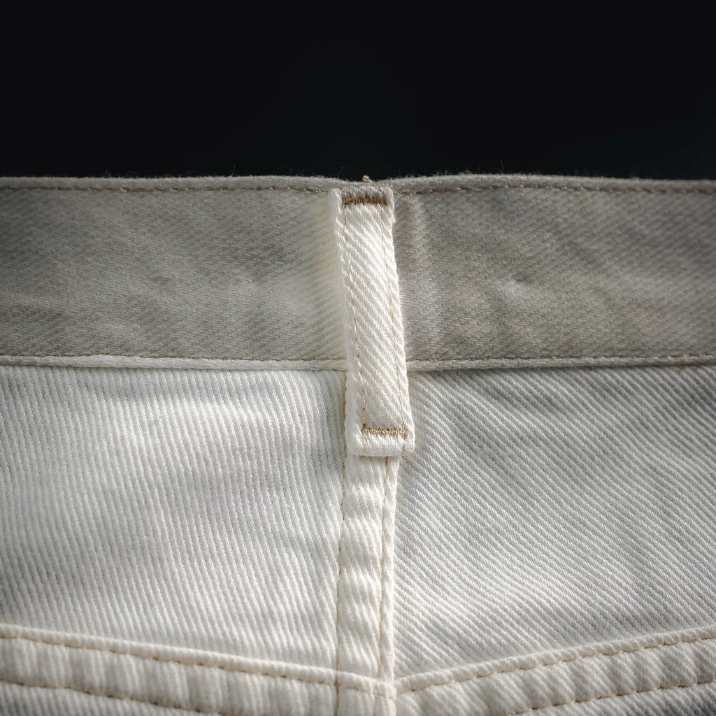 White pants waistband seam with inner label and visible stitched panel.