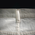 White pants waistband seam with inner label and visible stitched panel.