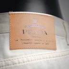 Prada logo leather label on the waistband of white pants.