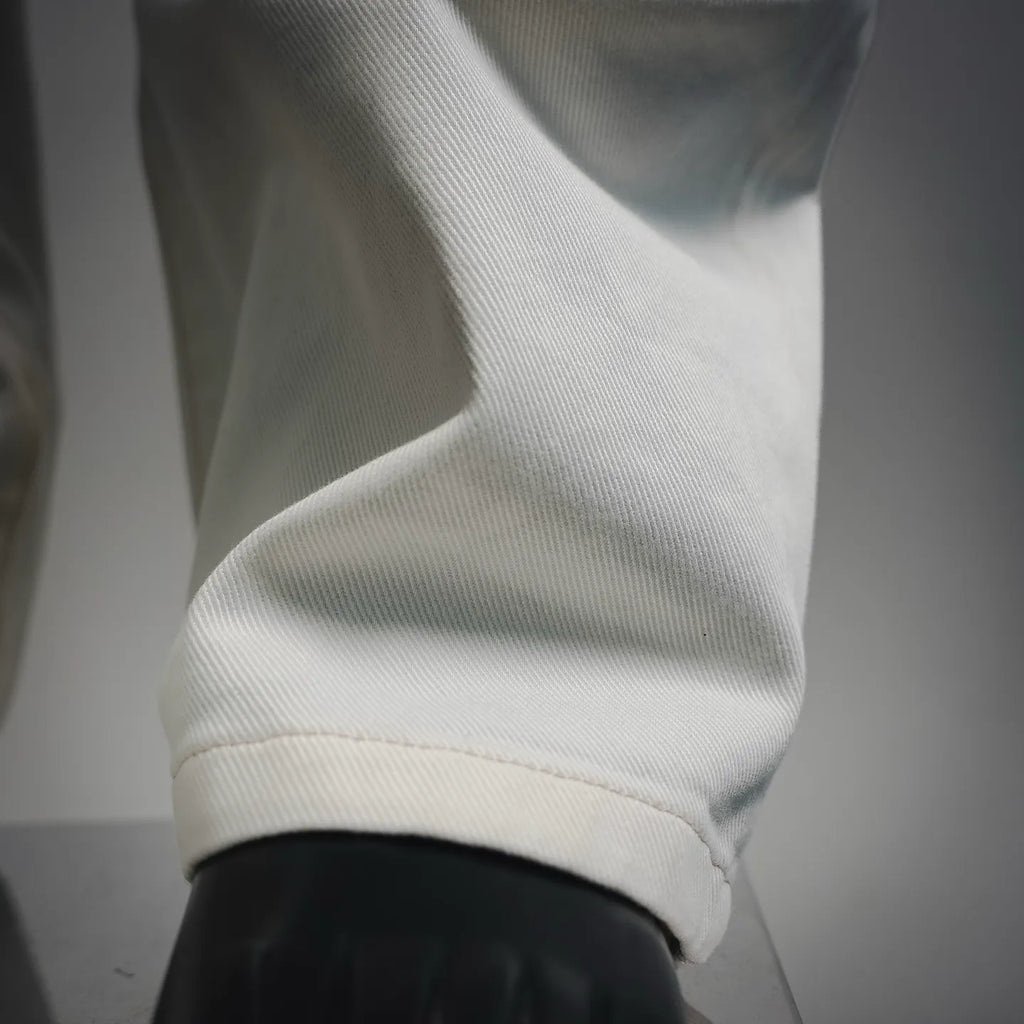White pants hem and cuff detail with a visible stitched seam.
