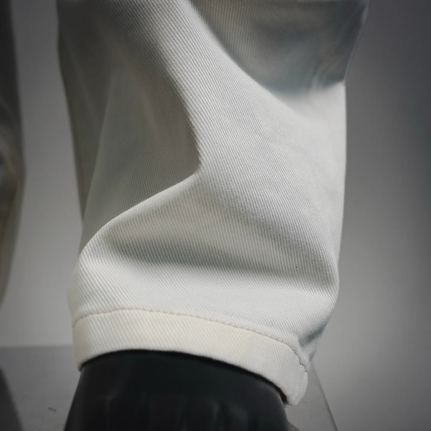 White pants hem and cuff detail with a visible stitched seam.