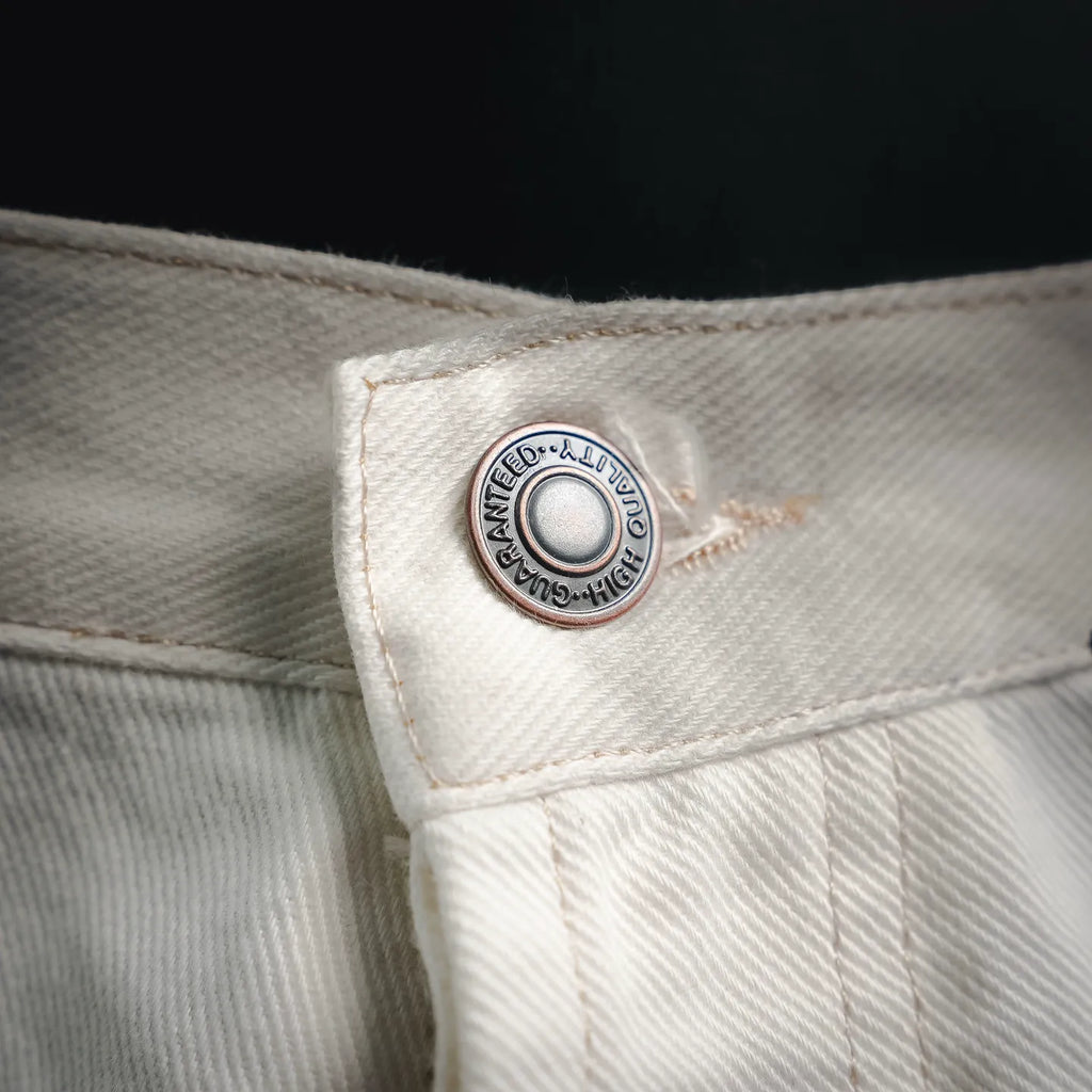 Round logo patch on white pants waistband with leather trim.
