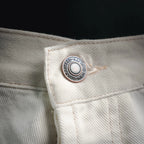 Round logo patch on white pants waistband with leather trim.