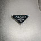 Prada Milano triangular logo patch on white fabric