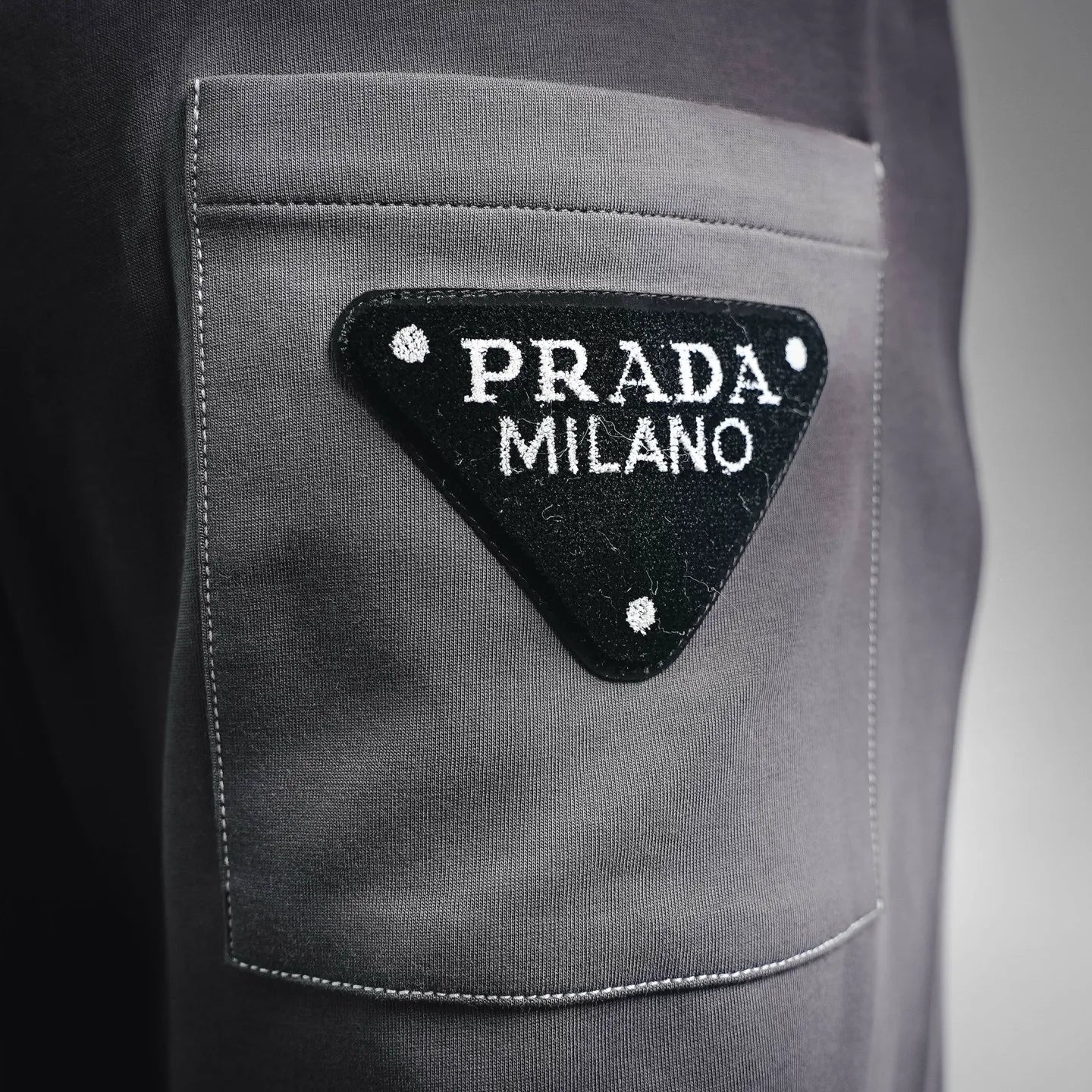 Dark gray pants pocket with triangular Prada Milano logo patch