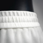 White Prada shorts waistband close-up with gathered elastic detail.