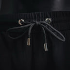 Black drawstring with metal aglets and eyelets at elastic waistband