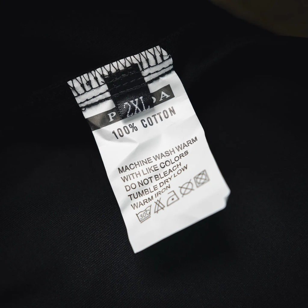 Black pants care label showing 100% cotton and machine wash warm