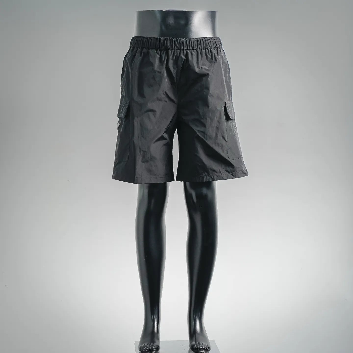 Dark nylon shorts-style pants with elastic waist and side cargo pockets