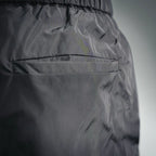 Dark nylon pants with stitched paneling and textured fabric surface