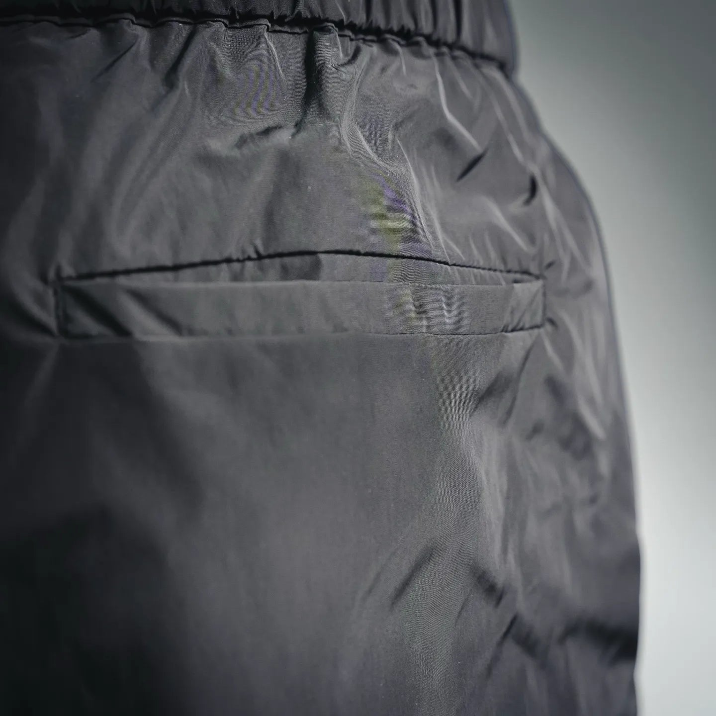 Dark nylon pants with stitched paneling and textured fabric surface