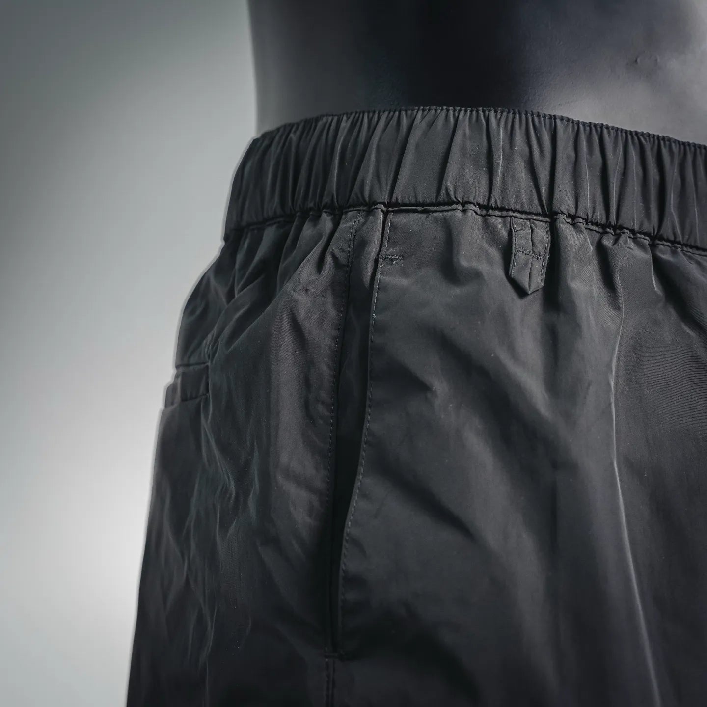 Dark nylon pants waistband with elastic and stitched seam details