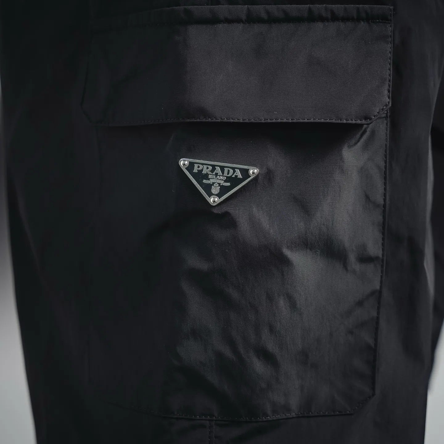Dark nylon pocket with triangular Prada logo patch
