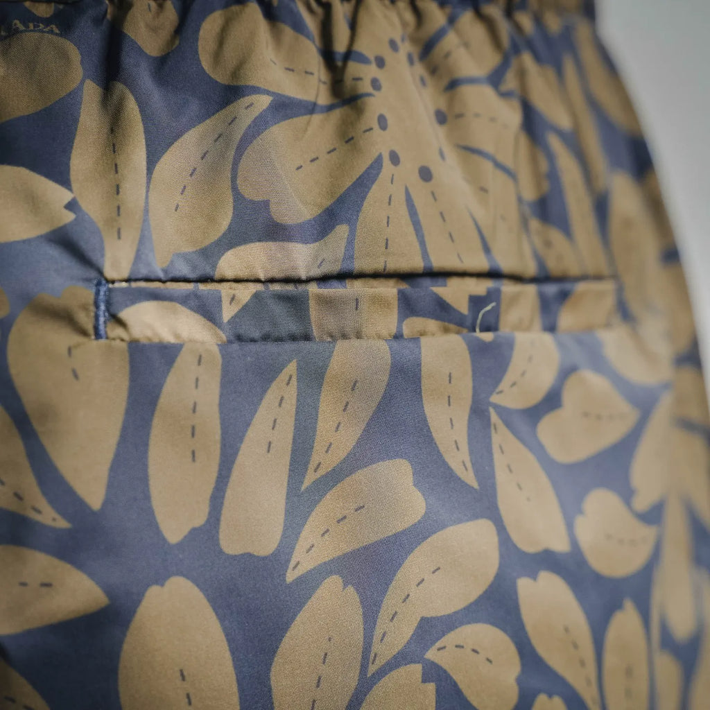 Blue and tan floral leaf fabric print on Prada shorts, close-up view