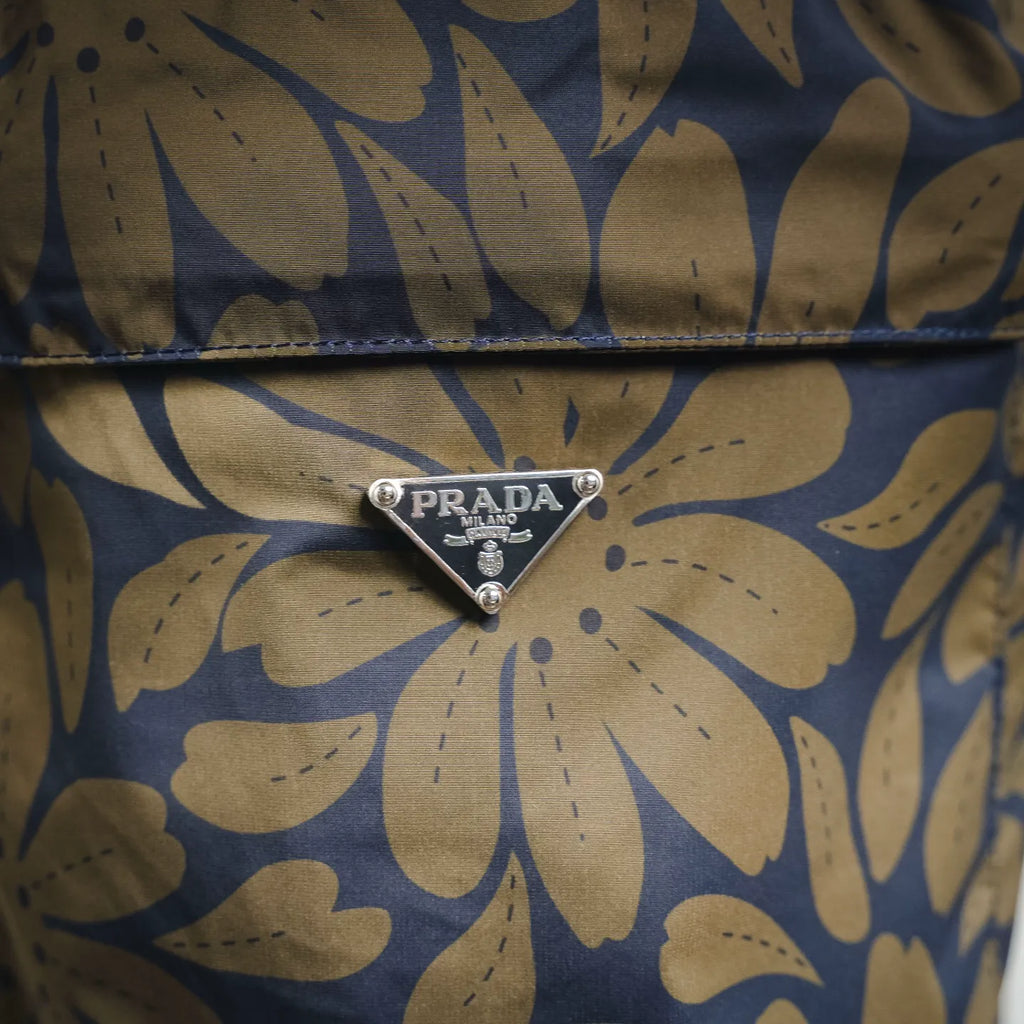 Prada logo triangle metal detail on blue and tan floral shorts pocket