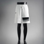 White drawstring shorts with black PRADA logo patch and striped hem trim