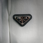Black triangle PRADA Milano logo patch on white shorts fabric