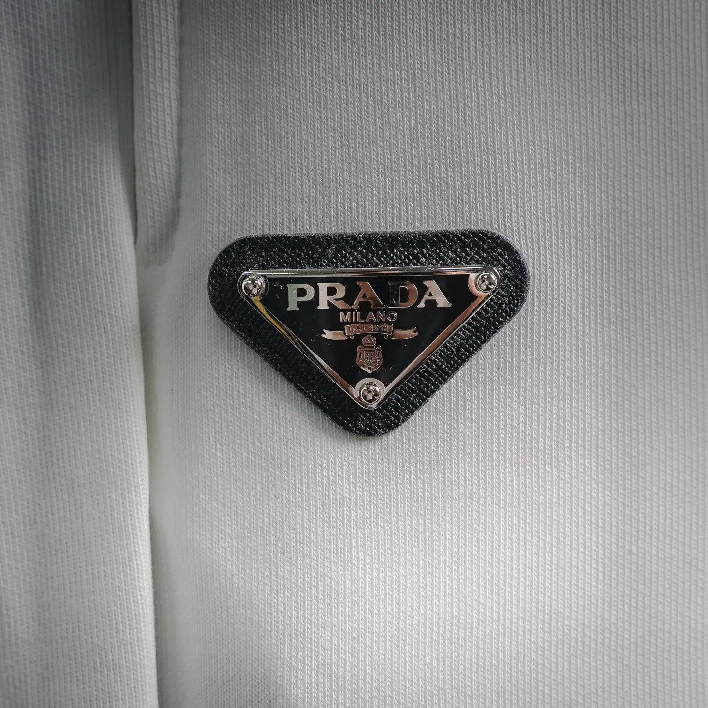 Black triangle PRADA Milano logo patch on white shorts fabric