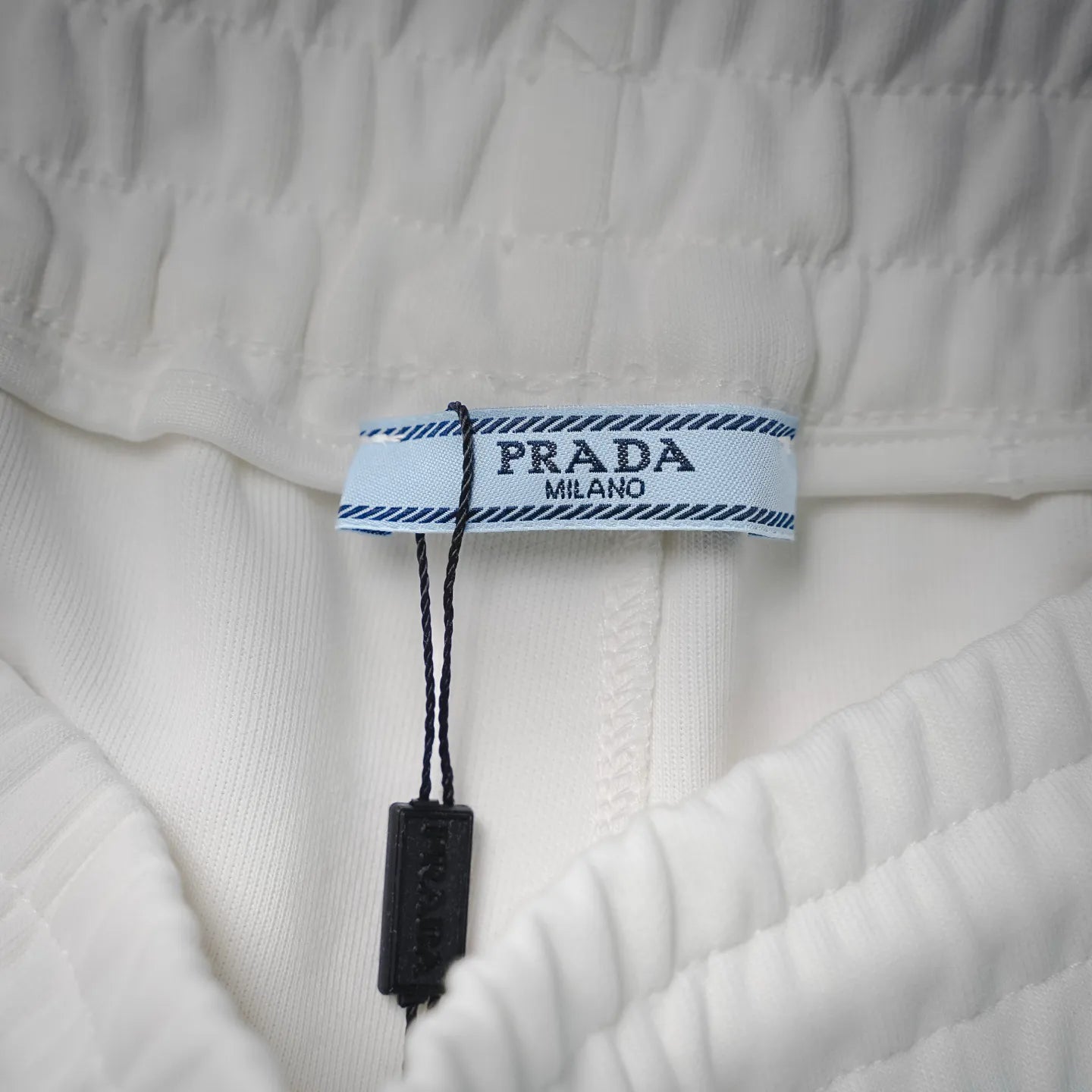 White shorts with PRADA Milano logo tag and blue trimmed label