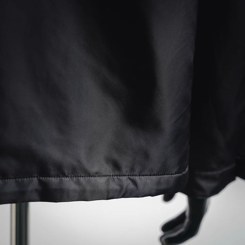 Black jacket hem with stitched trim and mannequin hand
