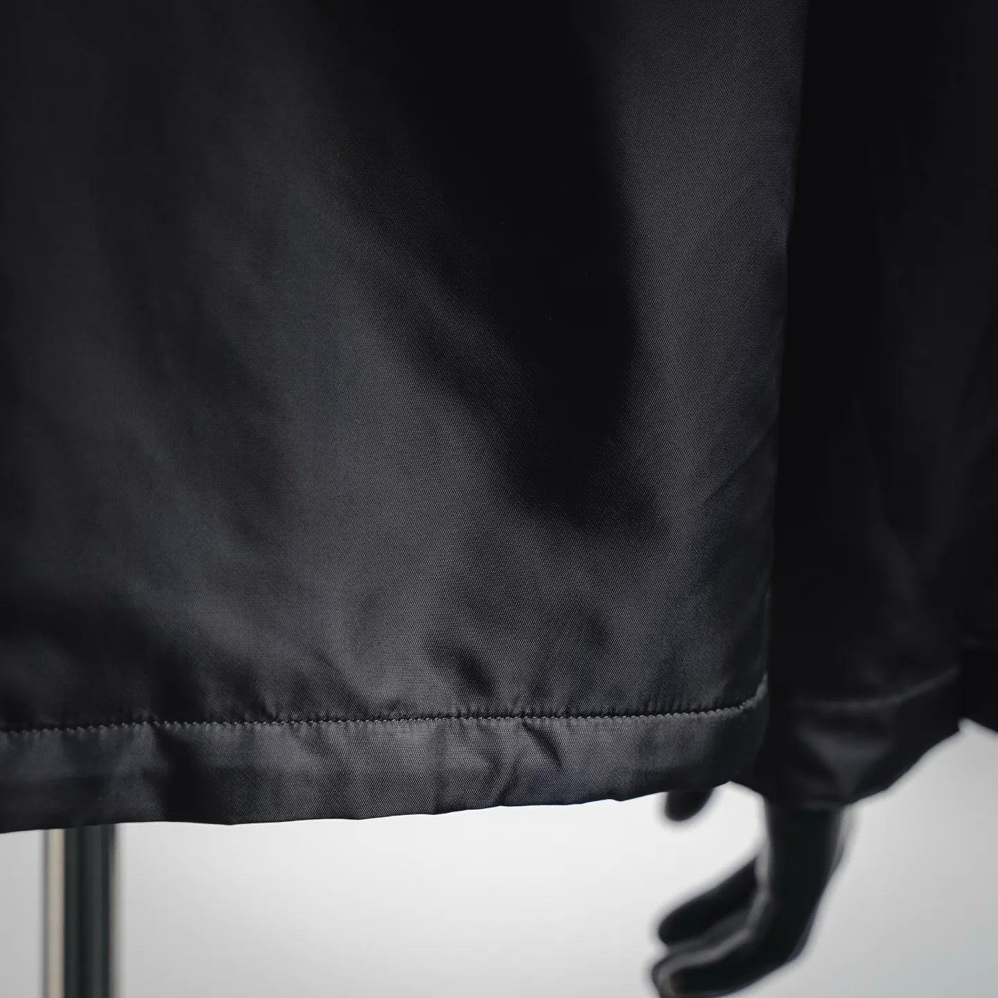 Black jacket hem with stitched trim and mannequin hand