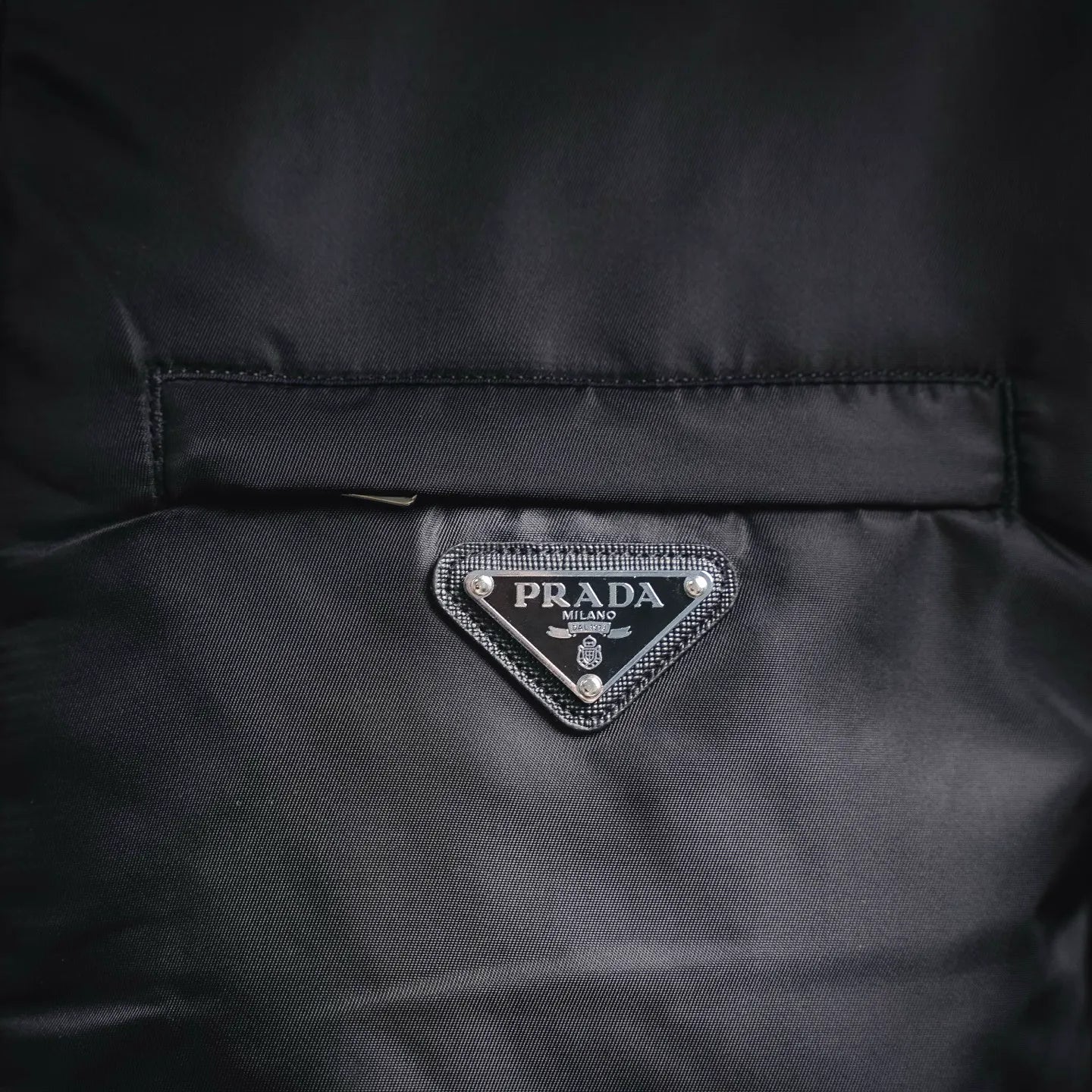 Prada logo triangle patch on front panel of black jacket