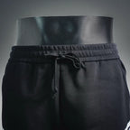 Black shorts with drawstring tie at elastic waist, front close-up