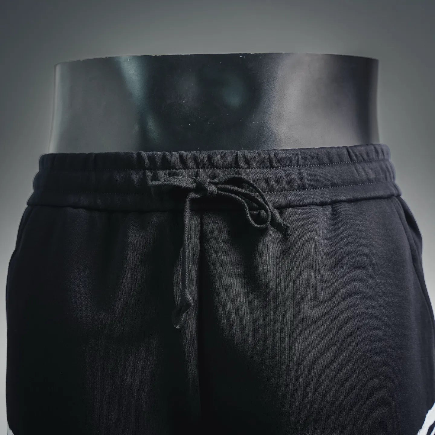 Black shorts with drawstring tie at elastic waist, front close-up