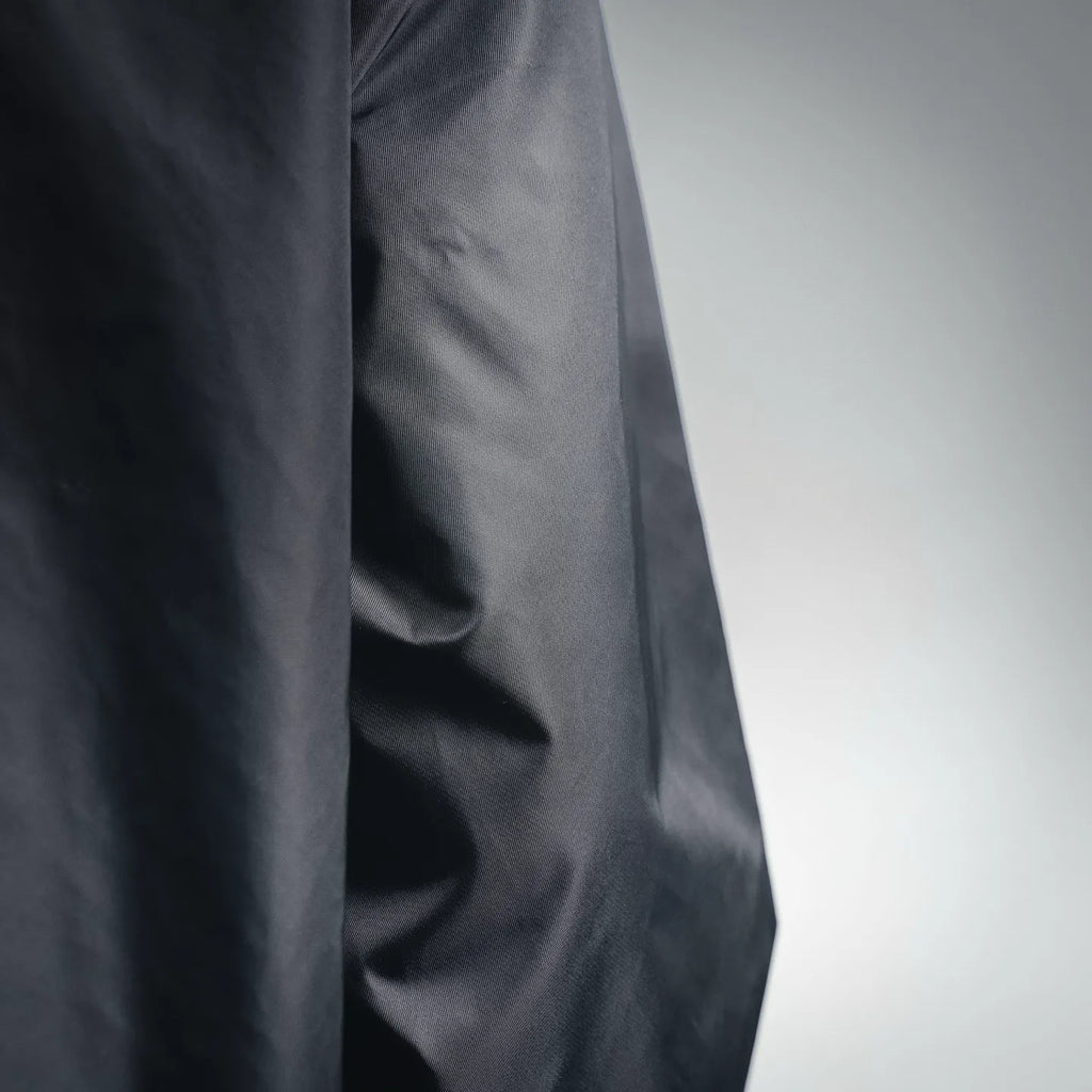 Close-up of dark gray jacket fabric with smooth weave and subtle creasing