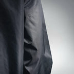 Close-up of dark gray jacket fabric with smooth weave and subtle creasing