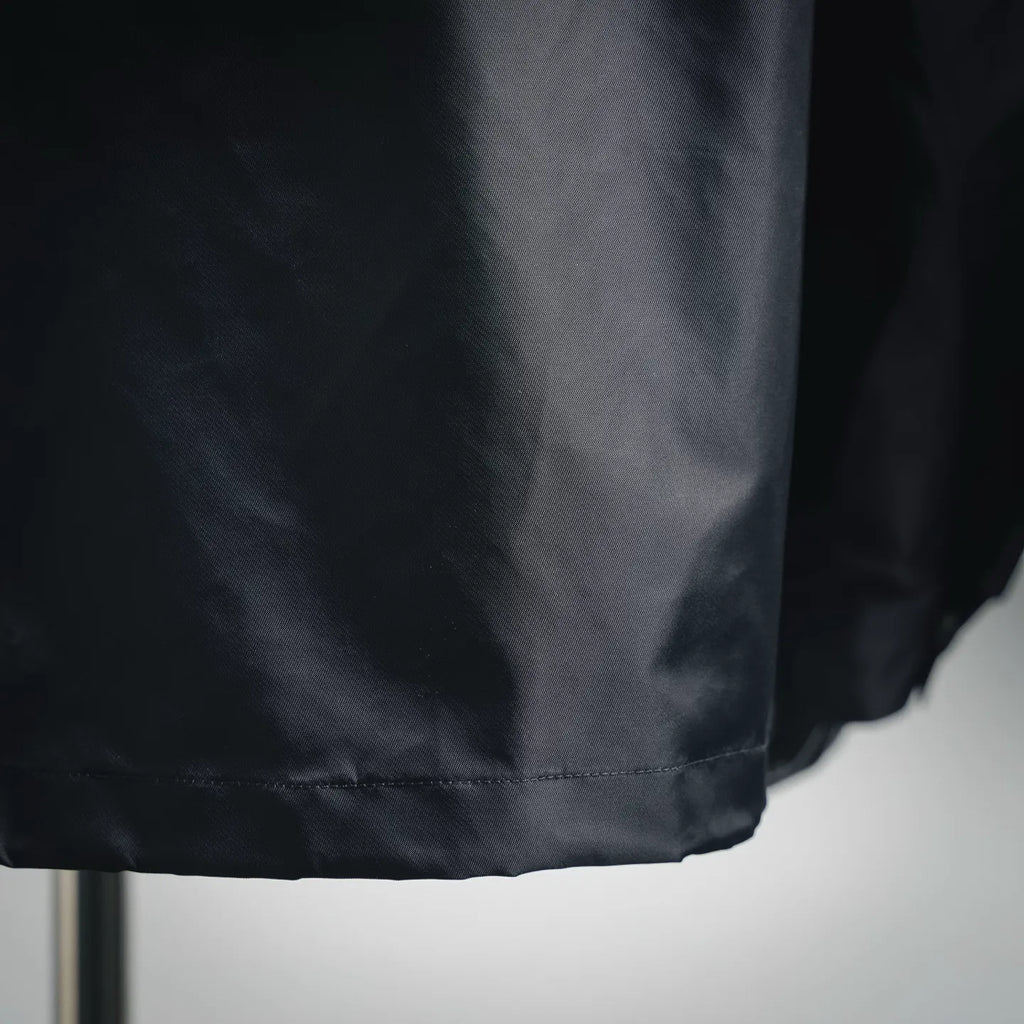 Dark gray jacket hem detail with double-stitched edge and gathered bottom