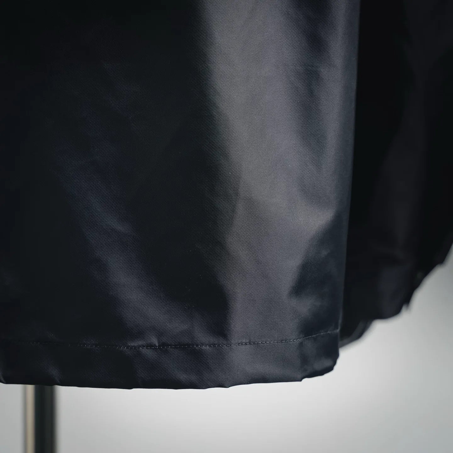 Dark gray jacket hem detail with double-stitched edge and gathered bottom
