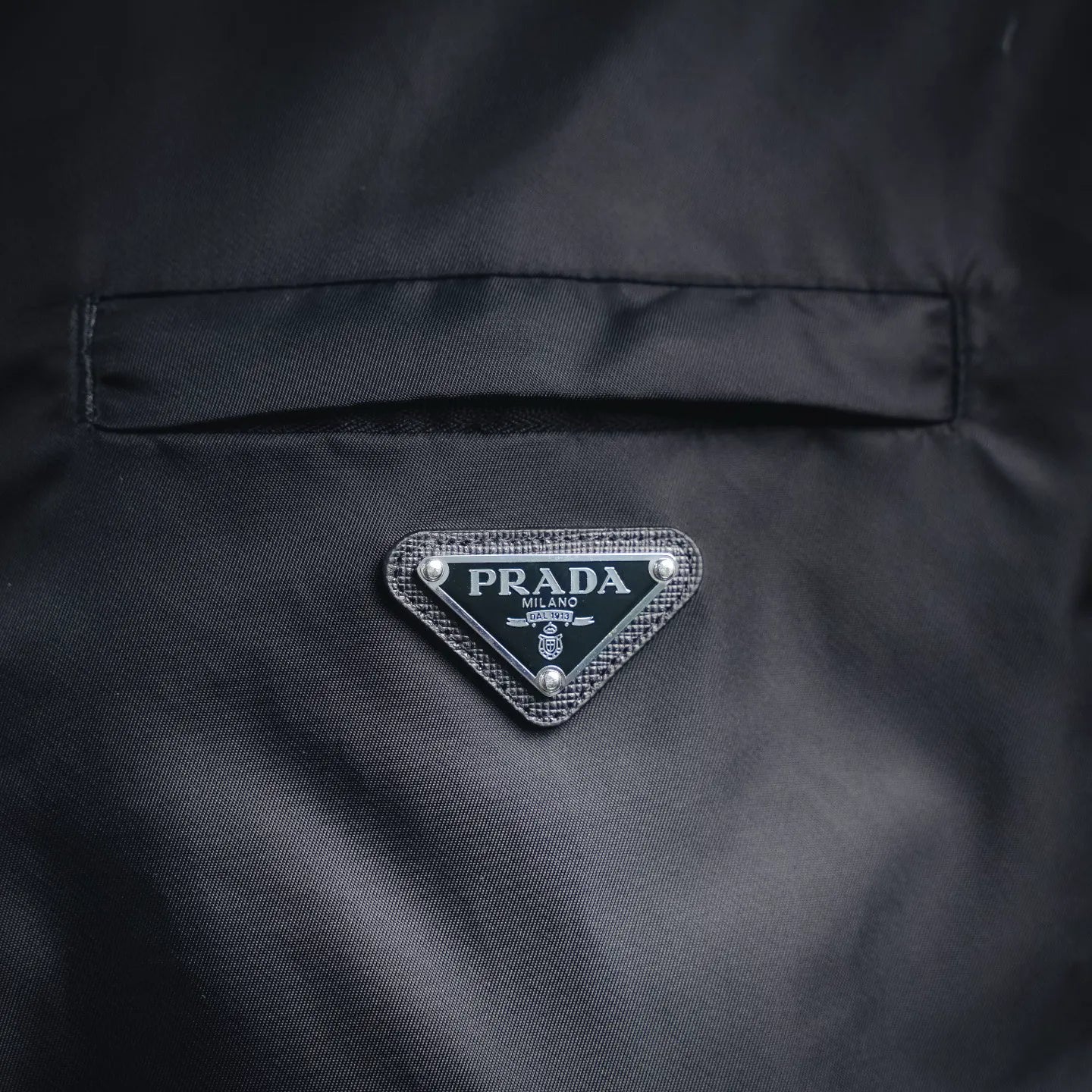 Prada logo badge on dark gray jacket back panel with stitched border